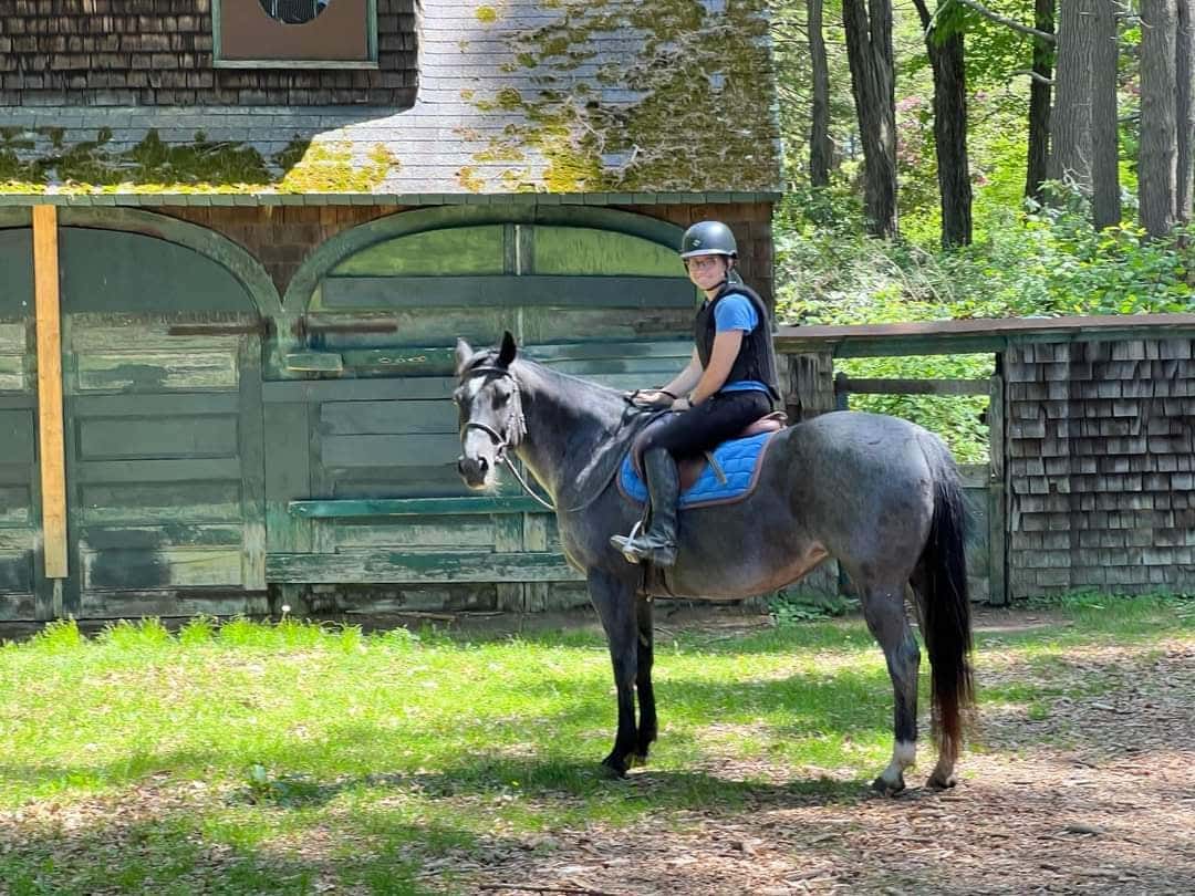 girl riding a black and white horse going over jumps